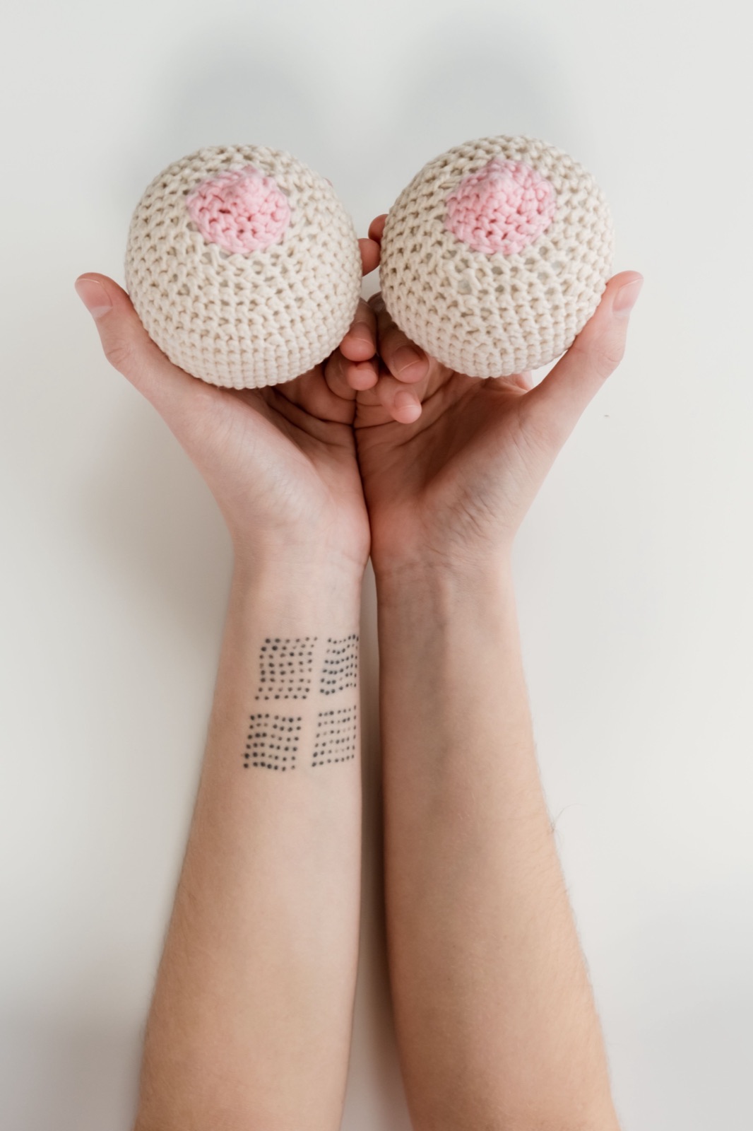 Hands holding two crocheted breast forms &mdash; a symbol of breast cancer awareness and support