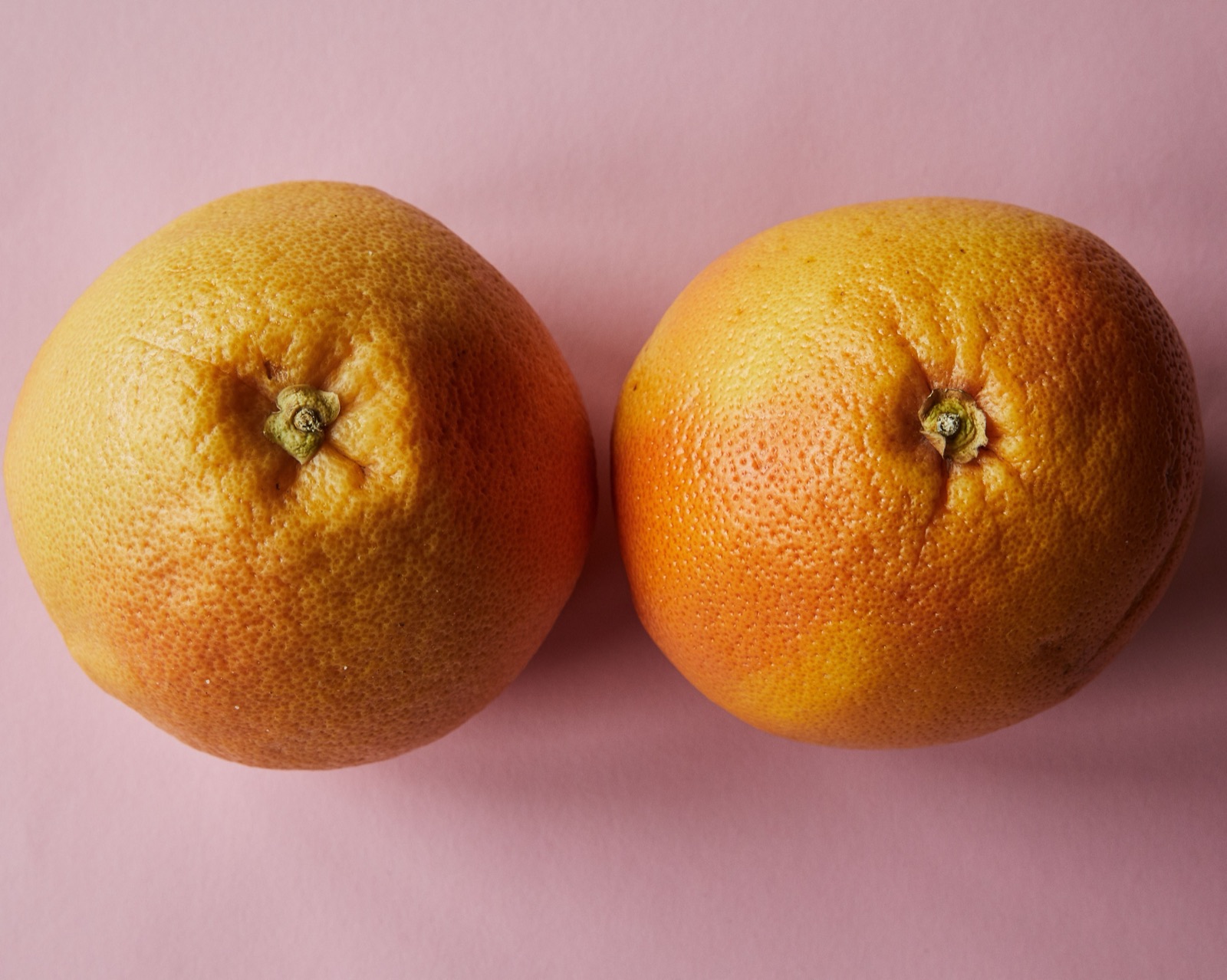Two grapefruit on a soft pink background, representing breast health awareness