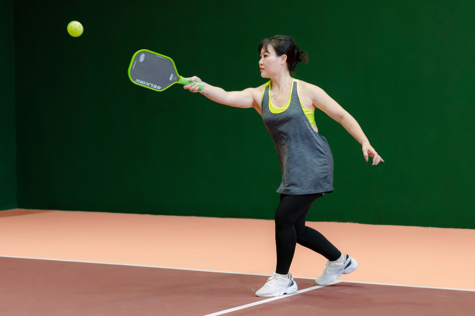 Woman playing pickleball, hitting a forehand shot